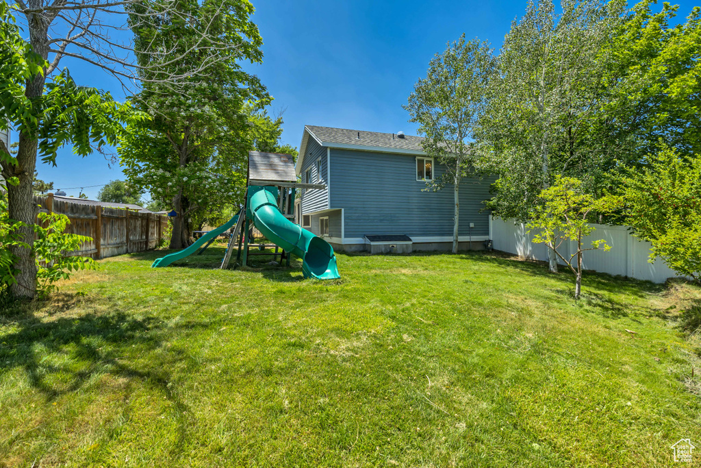 Fenced backyard featuring a playground