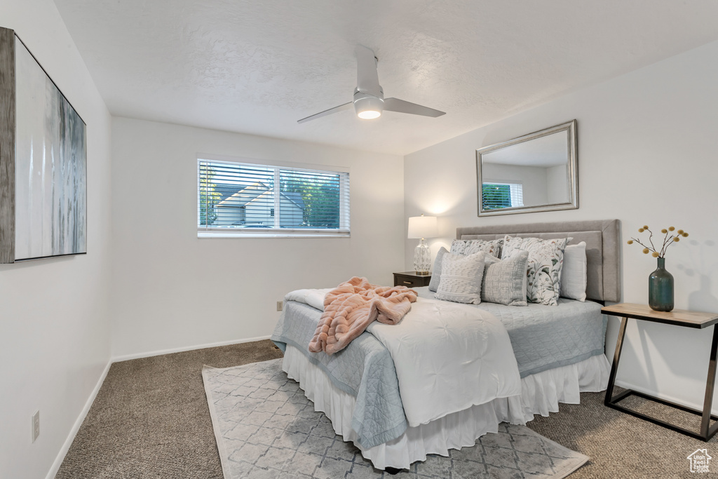 Bedroom with light carpet, a ceiling fan, and a textured ceiling