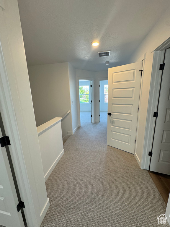 Hallway featuring a textured ceiling and carpet flooring