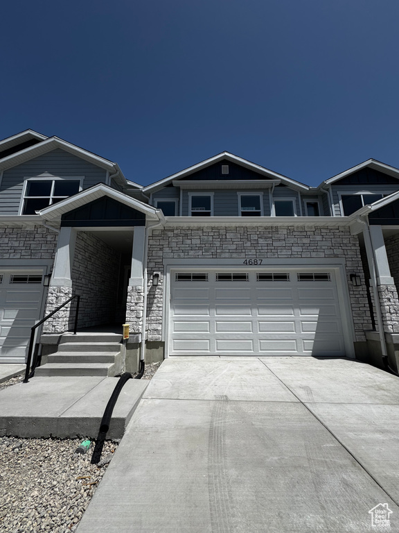 Ranch-style house featuring concrete driveway and stone siding