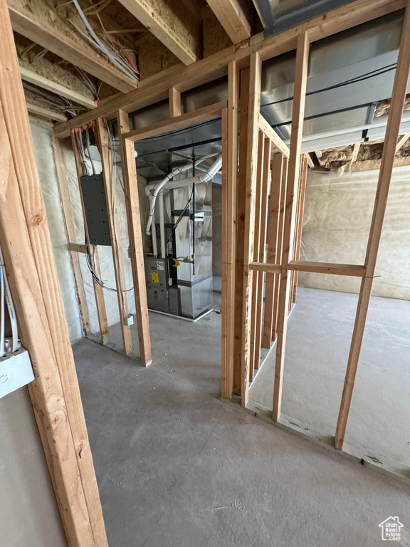 Unfinished below grade area with electric panel and heating unit