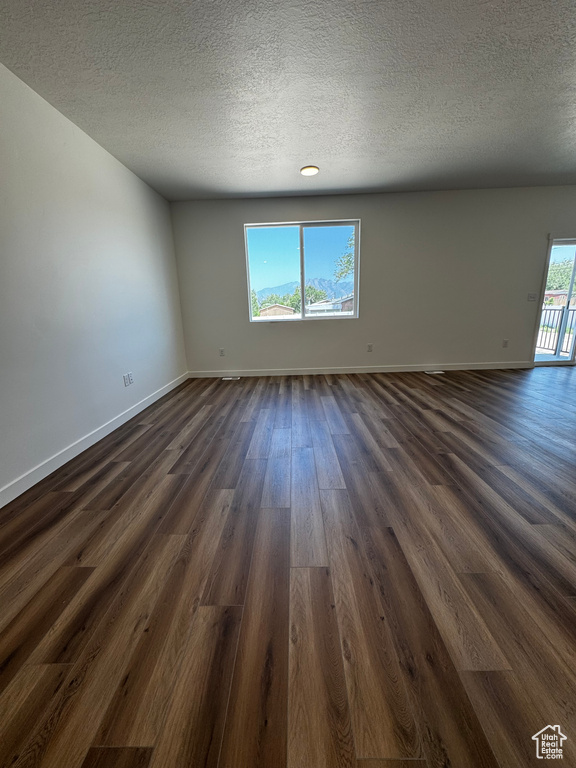 Empty room with dark wood-style flooring and a textured ceiling