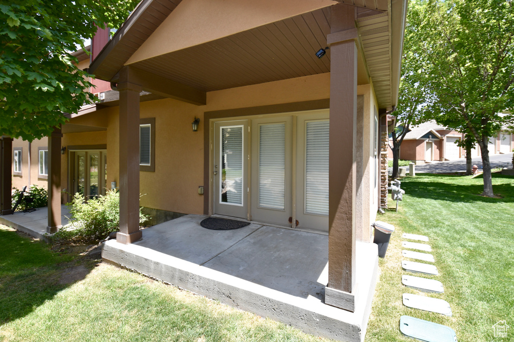 Property entrance featuring stucco siding, a patio area, and a lawn