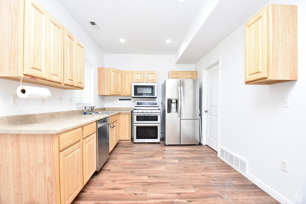 Kitchen with stainless steel appliances, light brown cabinetry, recessed lighting, light wood-style flooring, and light countertops