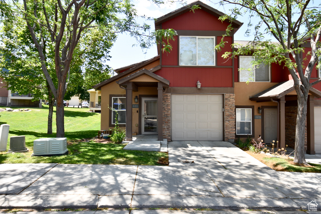 View of front of house featuring stone siding, stucco siding, a garage, a front yard, and concrete driveway