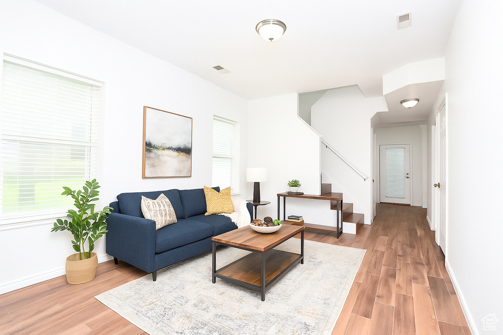 Living room featuring stairway, light wood finished floors, and healthy amount of natural light