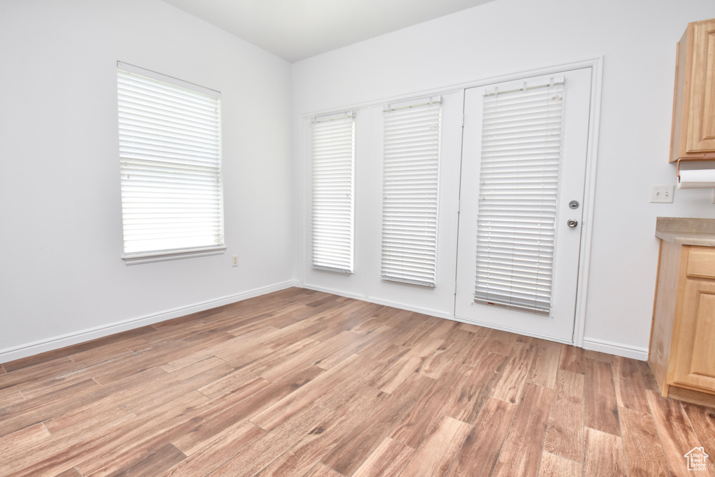 Unfurnished dining area featuring light wood-style flooring and baseboards