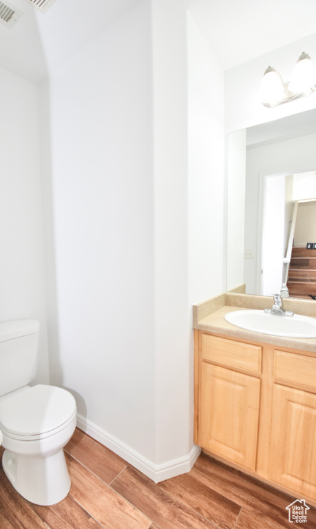 Half bath with wood finished floors and vanity