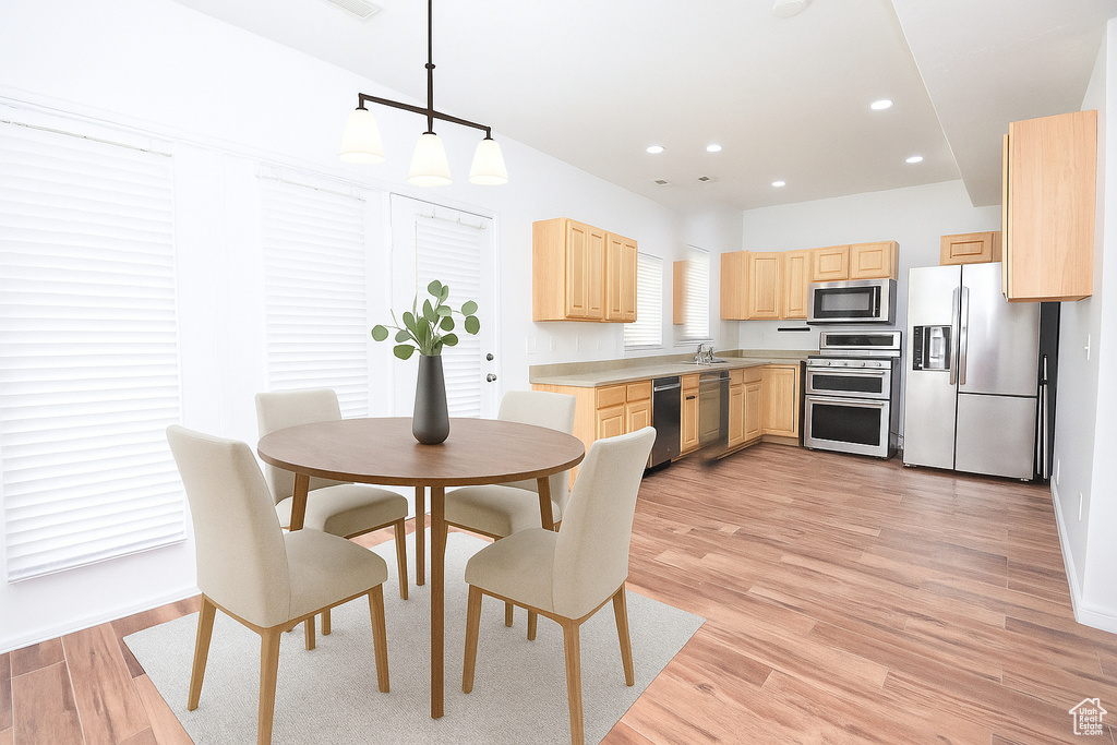 Kitchen featuring appliances with stainless steel finishes, light brown cabinets, light wood-style flooring, recessed lighting, and decorative light fixtures
