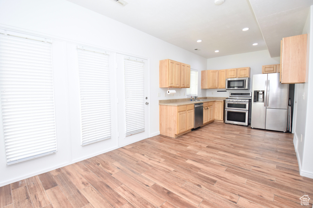 Kitchen featuring appliances with stainless steel finishes, light brown cabinets, light wood finished floors, light countertops, and recessed lighting