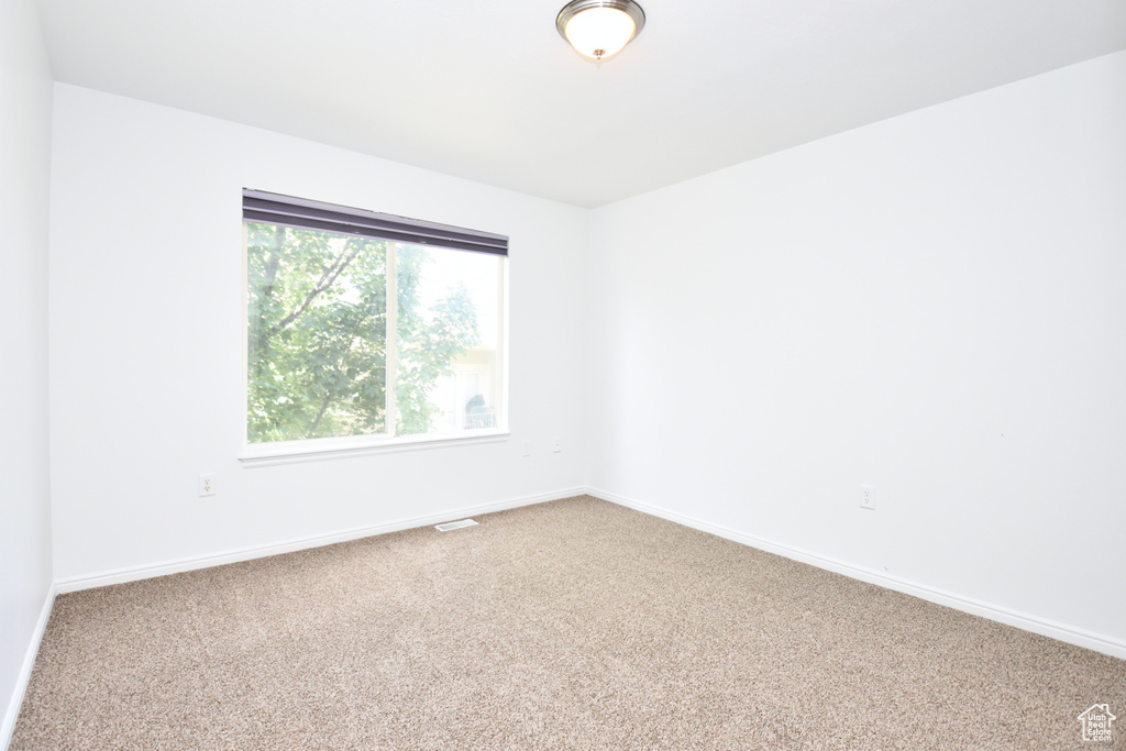 Carpeted spare room featuring baseboards
