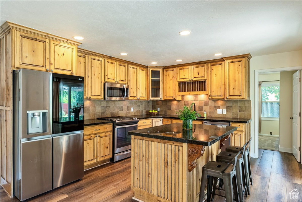 Kitchen with stainless steel appliances, dark wood-style floors, tasteful backsplash, a kitchen island, and recessed lighting
