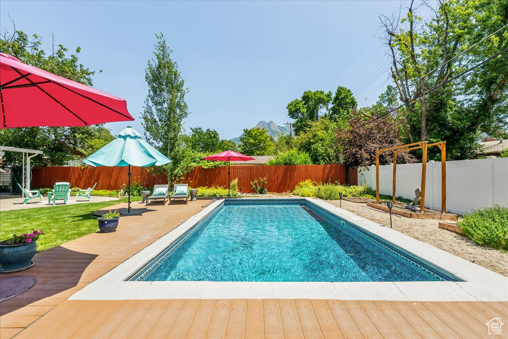 View of swimming pool featuring a wooden deck, a fenced backyard, and a patio area