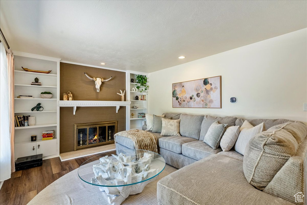 Living room featuring wood finished floors, recessed lighting, a fireplace, and built in features