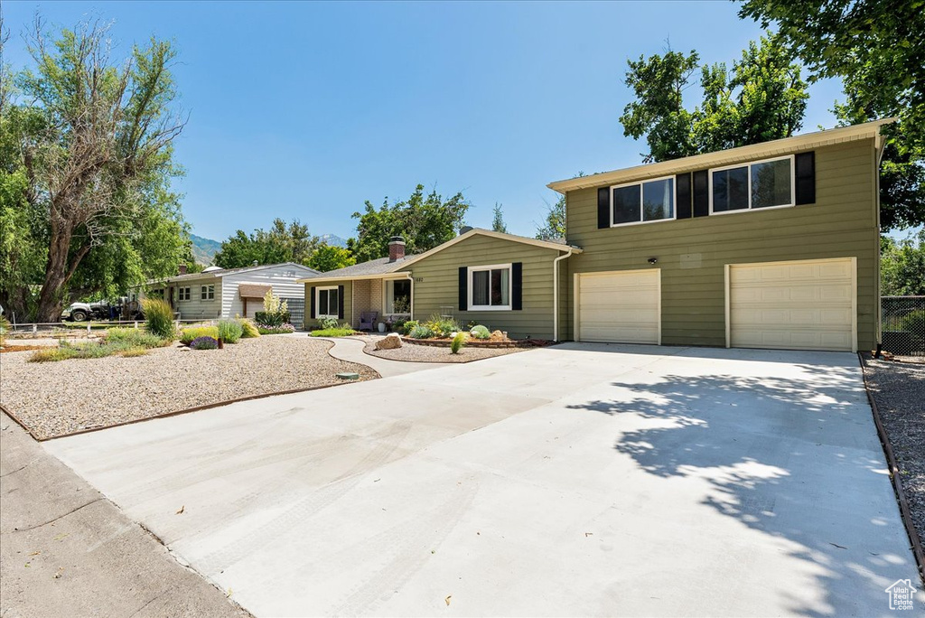 View of front of property with concrete driveway and an attached garage