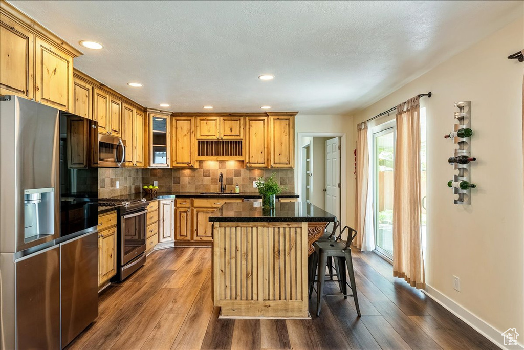 Kitchen featuring appliances with stainless steel finishes, dark wood-style floors, a center island, backsplash, and glass insert cabinets
