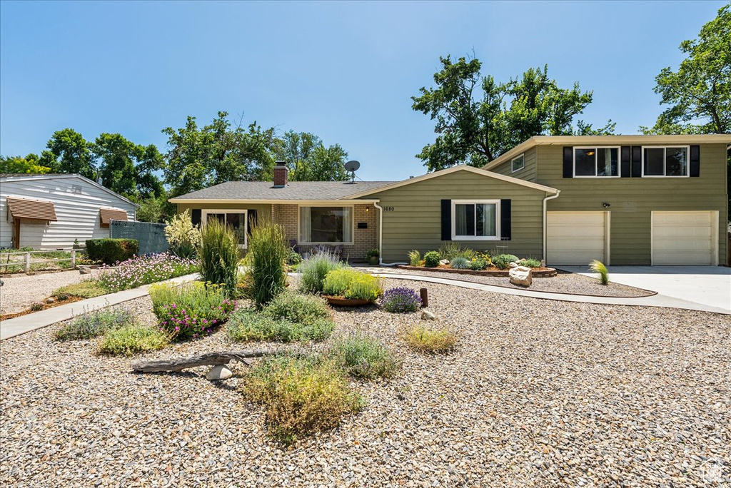 View of front of house featuring driveway, a chimney, and an attached garage