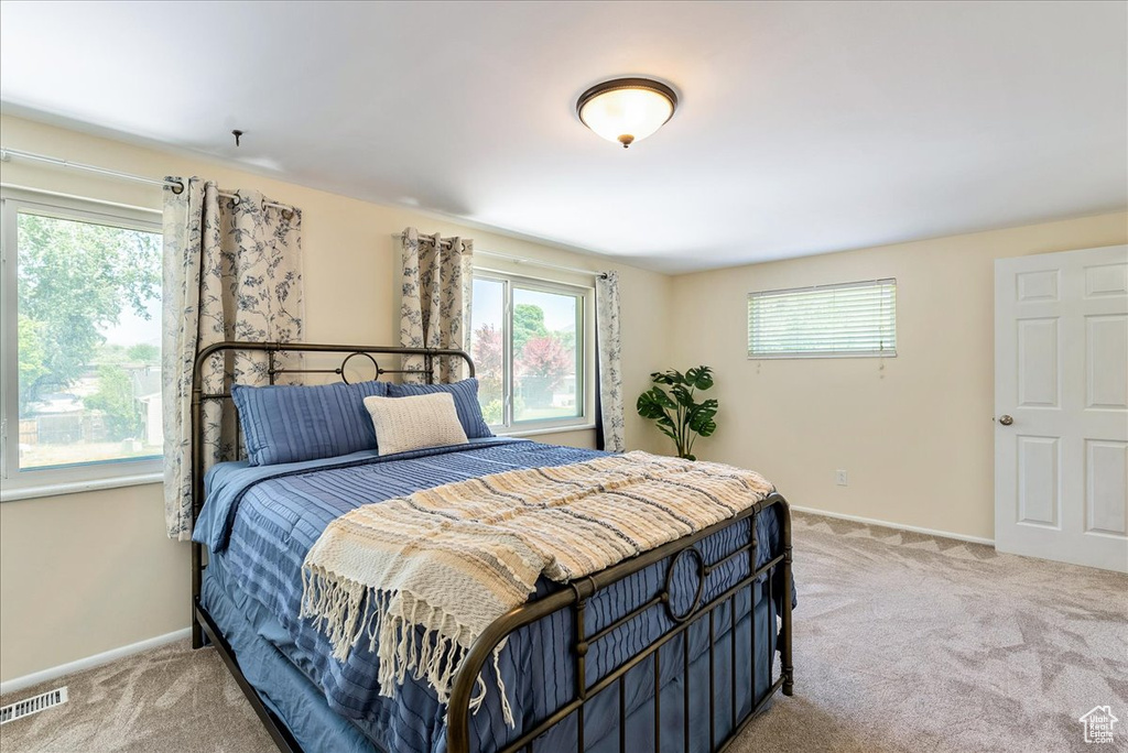 Bedroom featuring light colored carpet and multiple windows