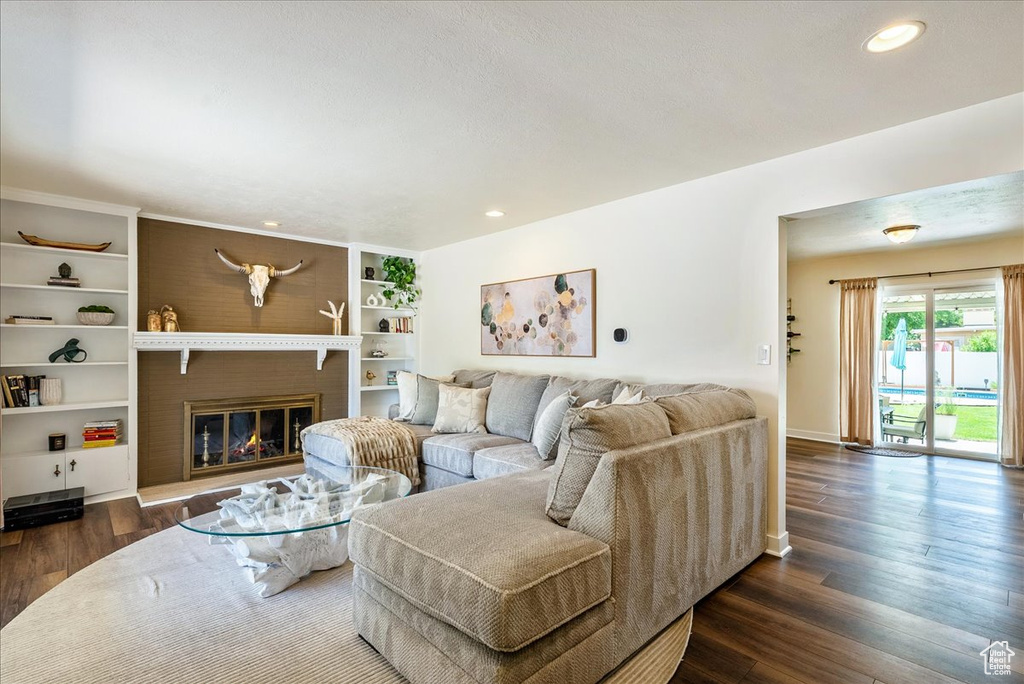 Living area with dark wood-type flooring, a glass covered fireplace, and recessed lighting