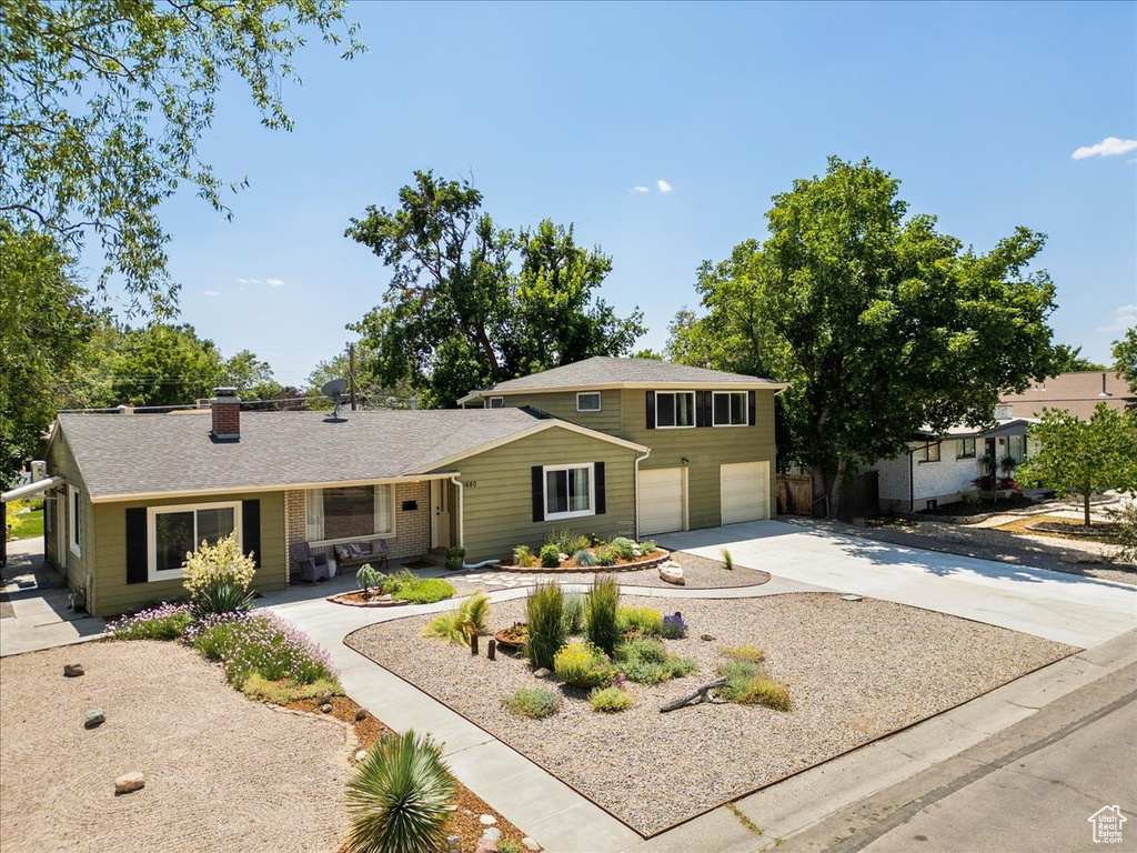View of front of house with an attached garage, driveway, and a chimney