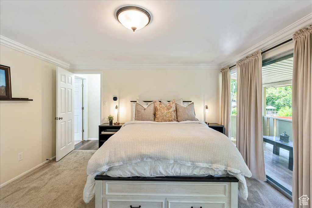 Bedroom with ornamental molding, light colored carpet, and access to exterior