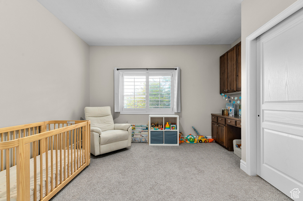 Bedroom featuring light carpet and a crib