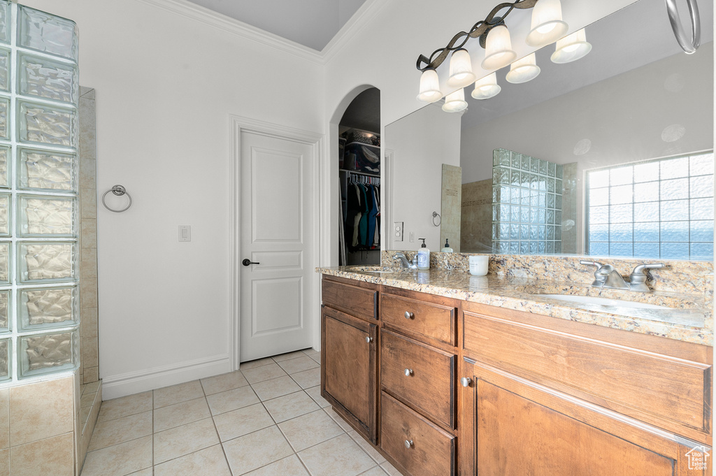 Full bathroom with crown molding, walk in shower, double vanity, tile patterned floors, and a walk in closet