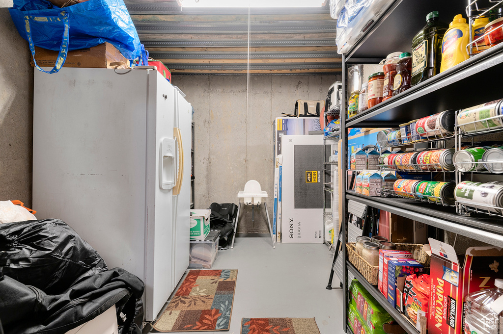 Below grade area with white refrigerator with ice dispenser