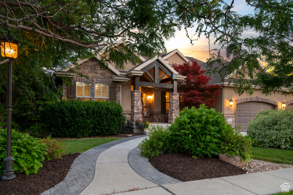 Craftsman-style home with stone siding, an attached garage, and stucco siding