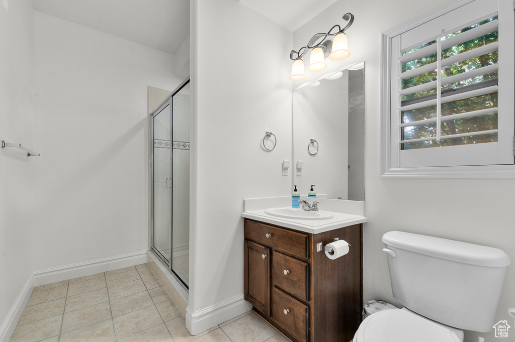 Full bath featuring vanity, tiled shower, and tile patterned flooring