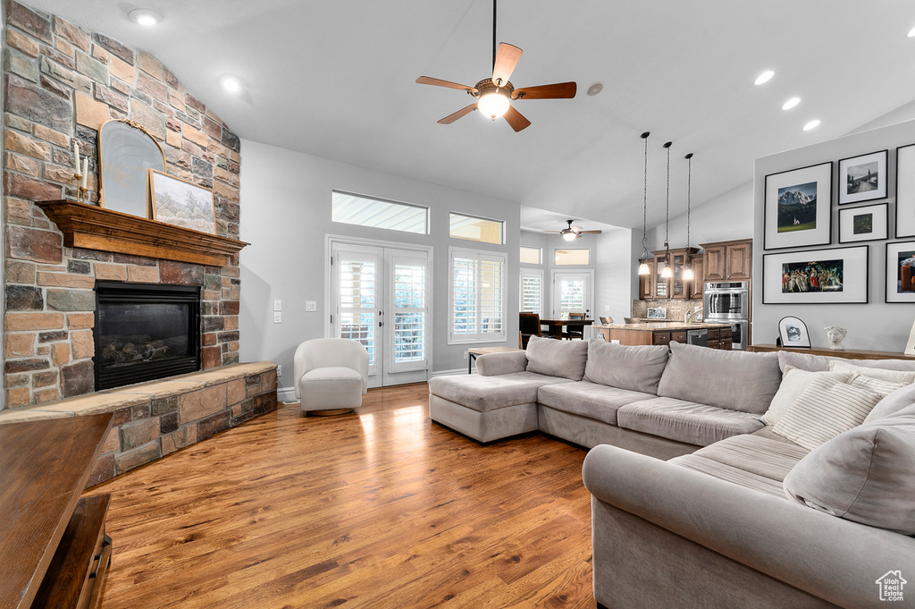 Living area featuring a ceiling fan, a fireplace, light wood-type flooring, high vaulted ceiling, and recessed lighting