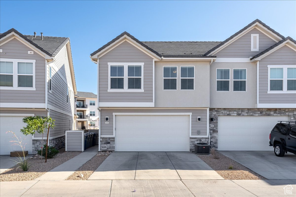 View of front of home with stone siding, an attached garage, and driveway