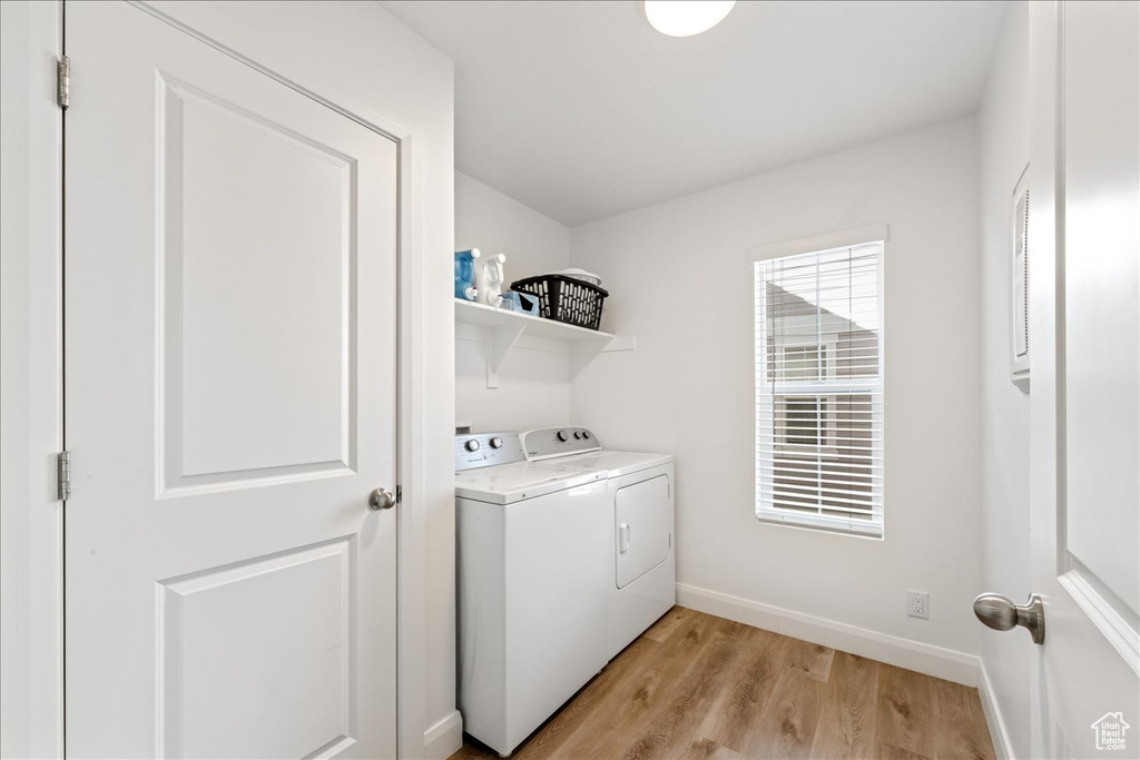 Laundry room with independent washer and dryer and light wood-type flooring