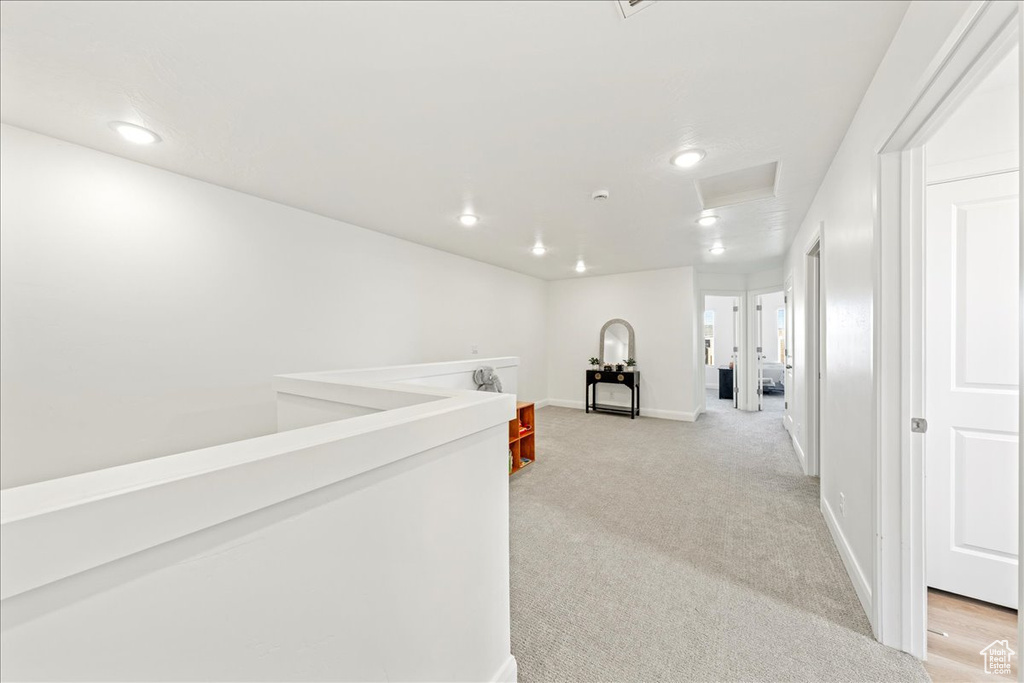 Hallway with attic access, light colored carpet, and recessed lighting