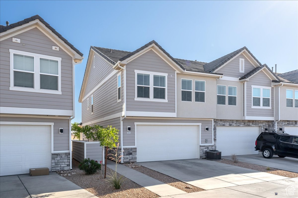 View of front of house with stone siding, an attached garage, and concrete driveway
