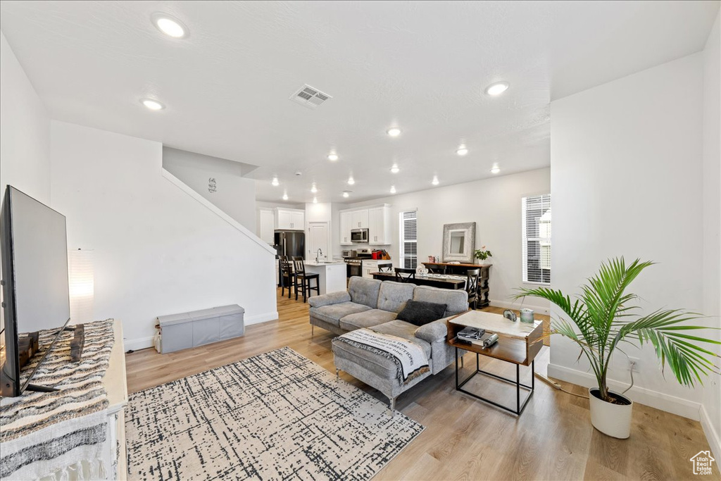 Living room featuring light wood finished floors, stairs, and recessed lighting