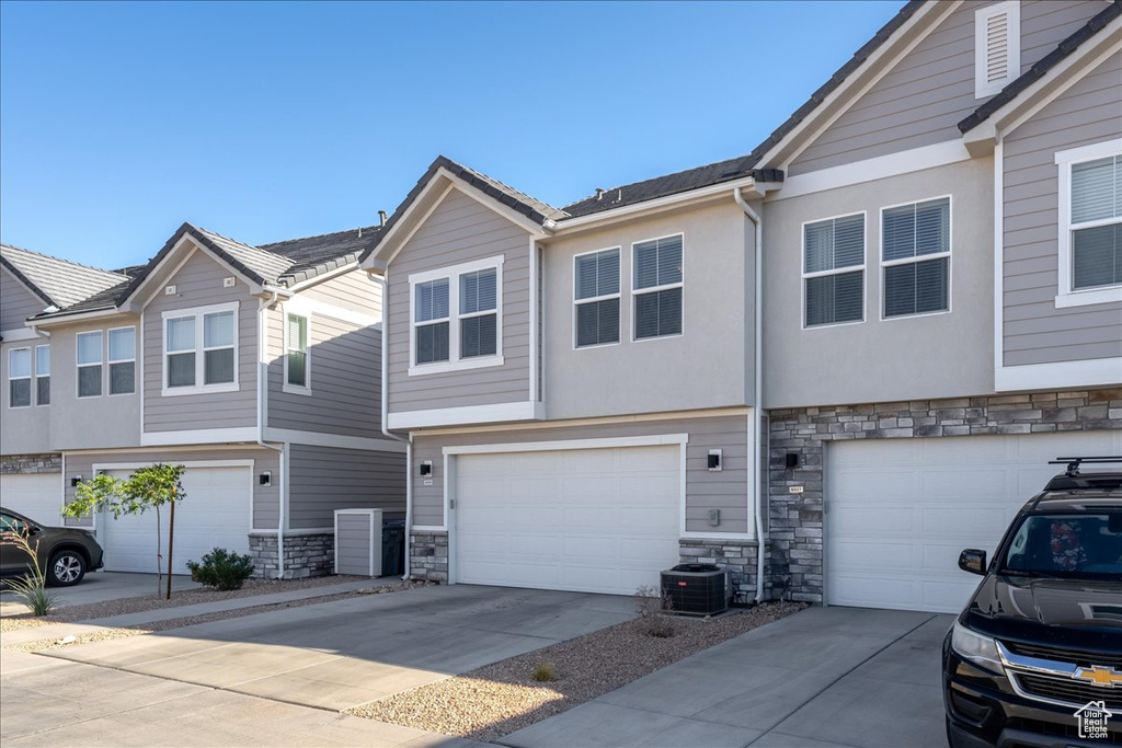 Townhome / multi-family property with stone siding, concrete driveway, and an attached garage