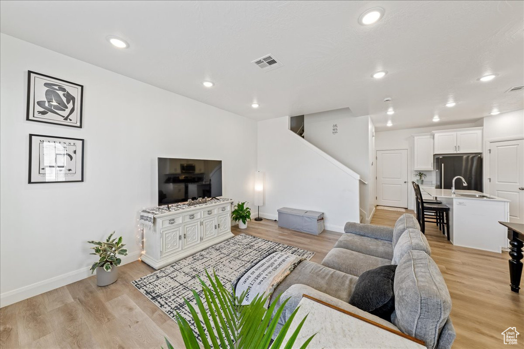 Living room featuring stairs, recessed lighting, and light wood-type flooring