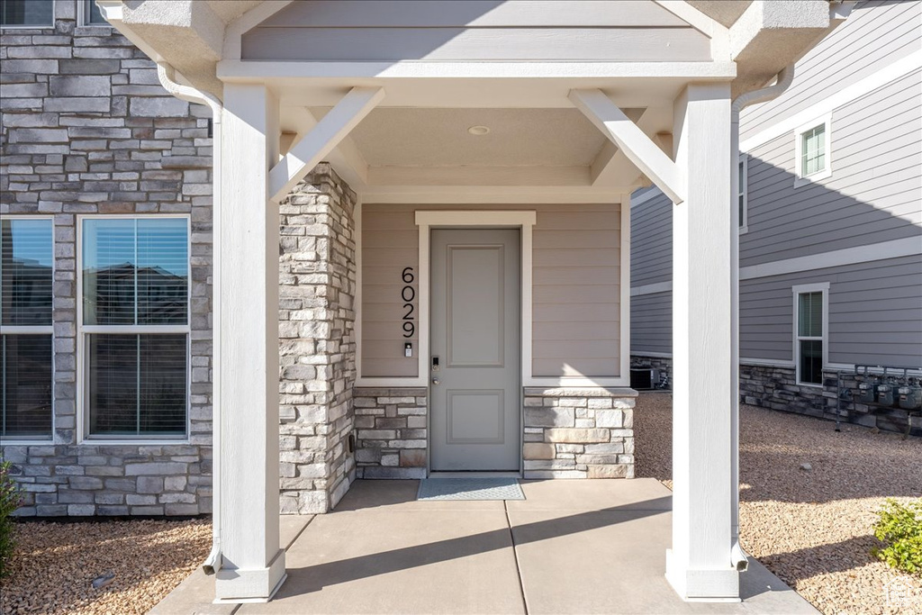 View of exterior entry featuring stone siding and covered porch