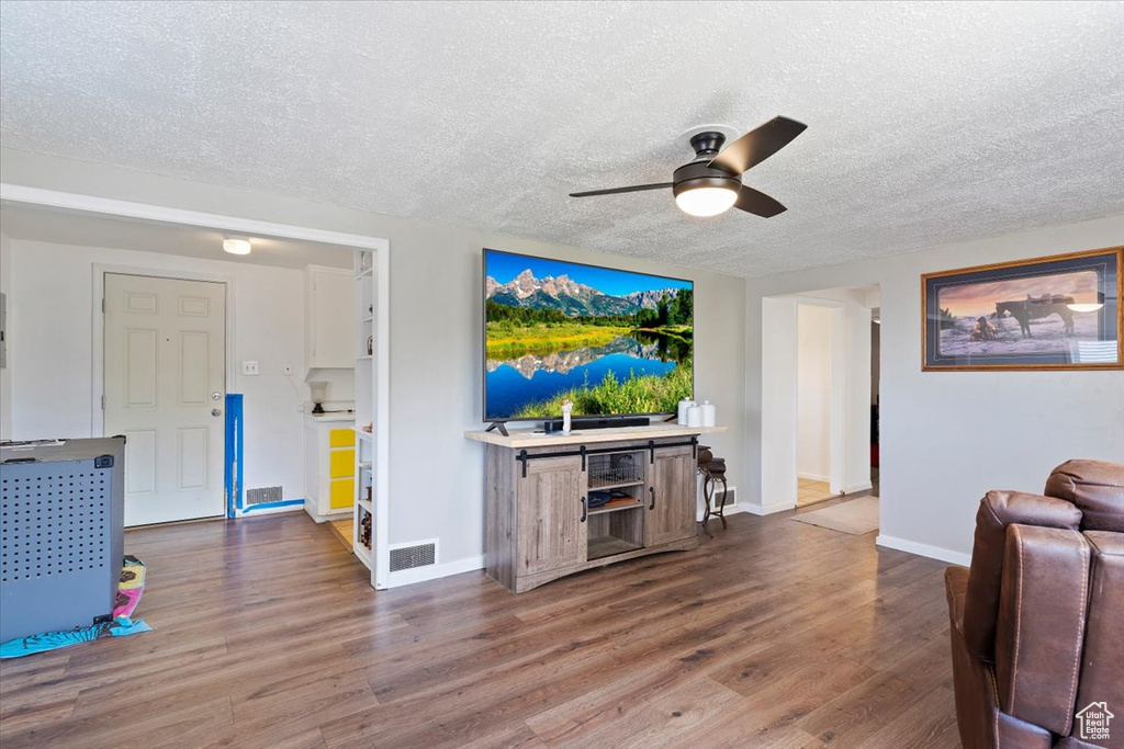Living room featuring ceiling fan, a textured ceiling, and wood finished floors