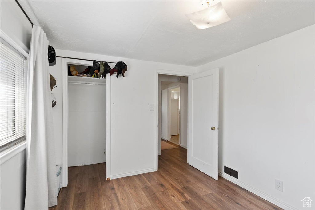 Unfurnished bedroom with wood finished floors and a closet