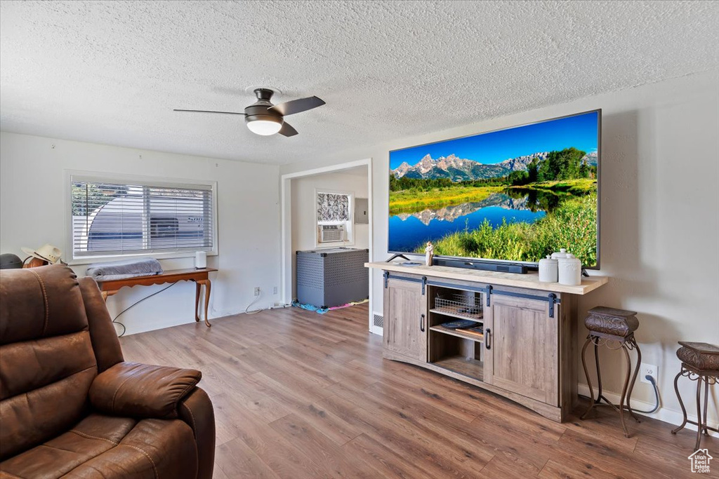 Living area featuring ceiling fan, a textured ceiling, wood finished floors, and cooling unit