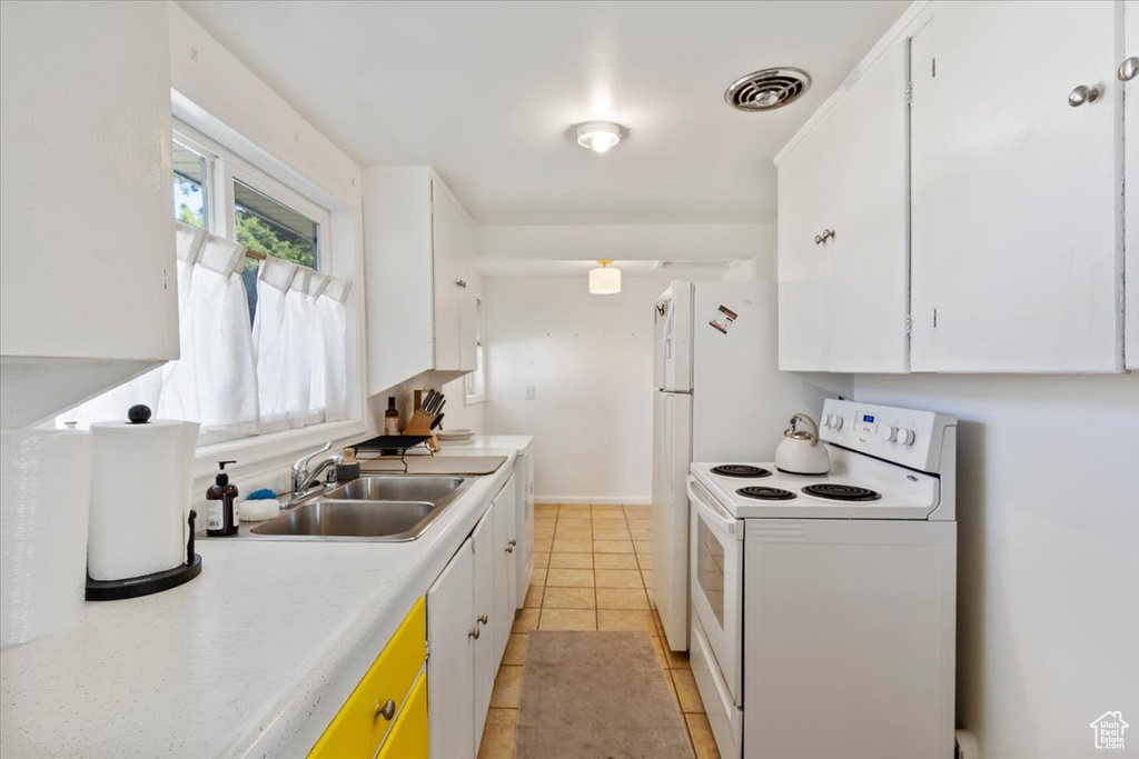 Kitchen featuring electric stove, light countertops, white cabinetry, and light tile patterned flooring