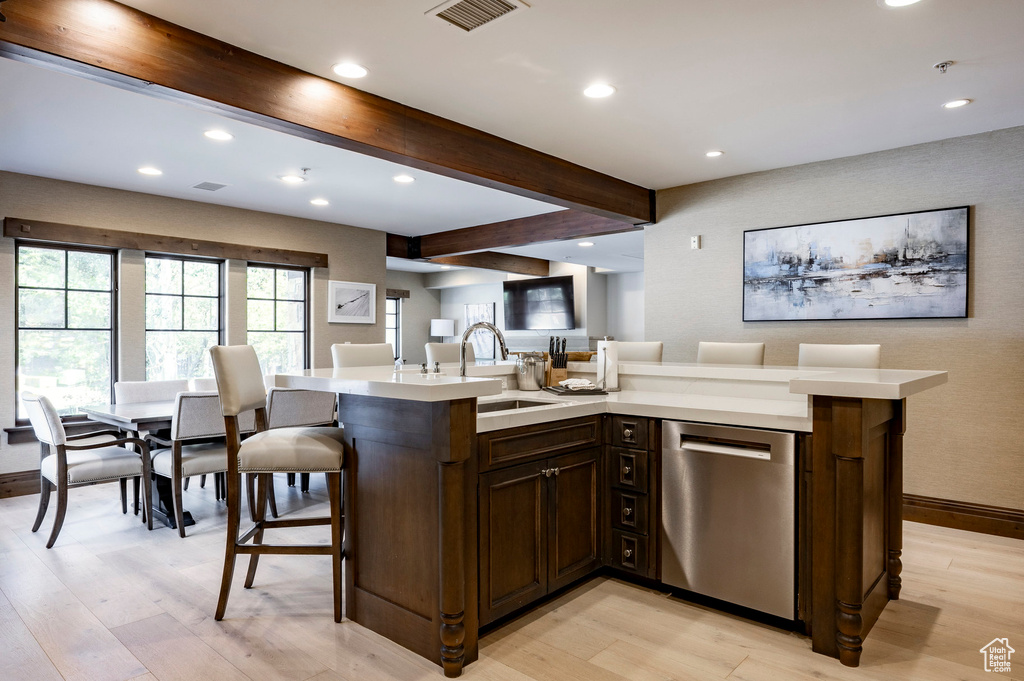 Kitchen featuring dishwasher, light countertops, light wood-type flooring, beamed ceiling, and recessed lighting