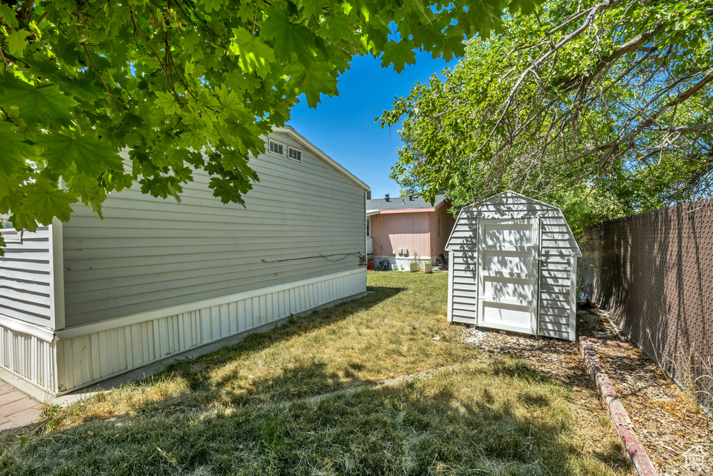 Fenced backyard featuring a storage unit