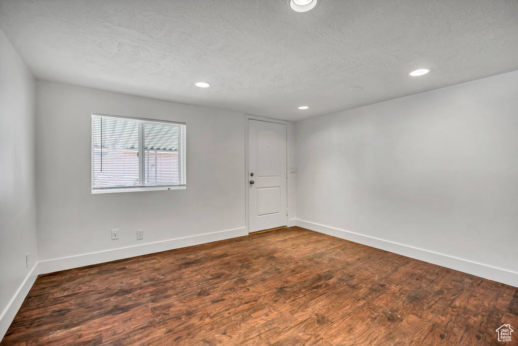 Empty room featuring dark wood-type flooring, recessed lighting, and a textured ceiling