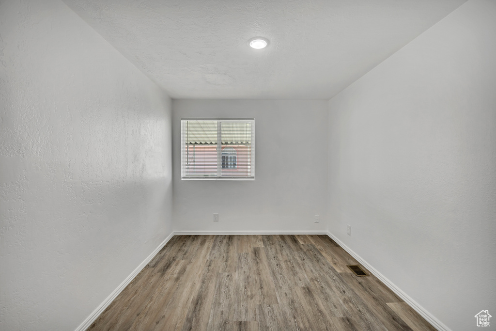 Unfurnished room with wood finished floors and baseboards