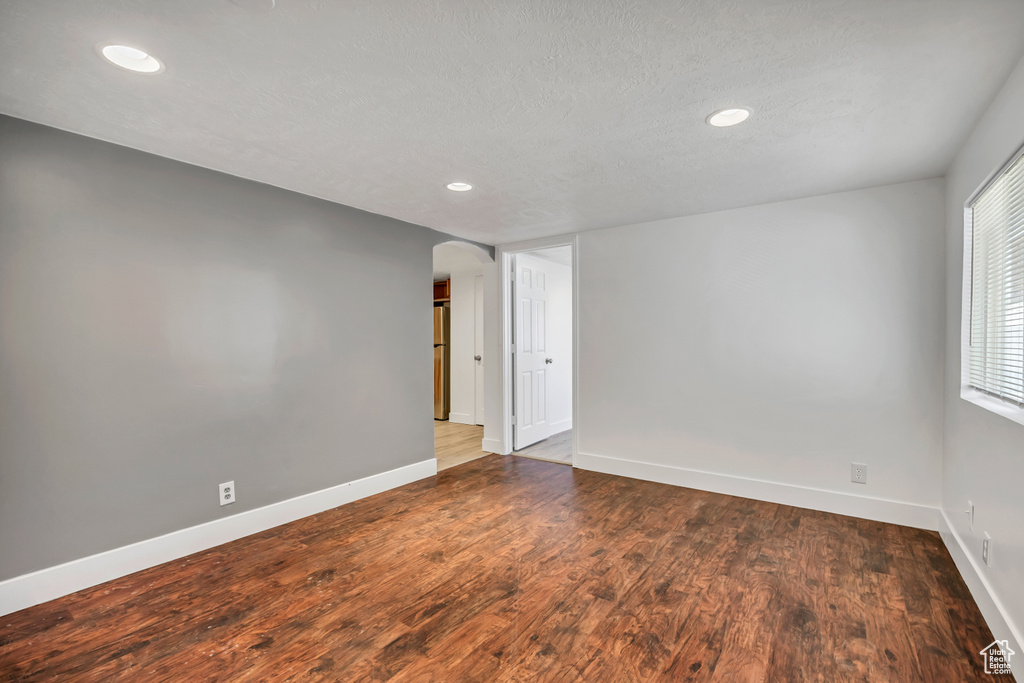 Unfurnished room featuring arched walkways, recessed lighting, and wood finished floors