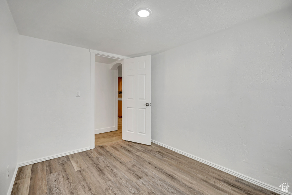 Spare room with arched walkways and wood finished floors