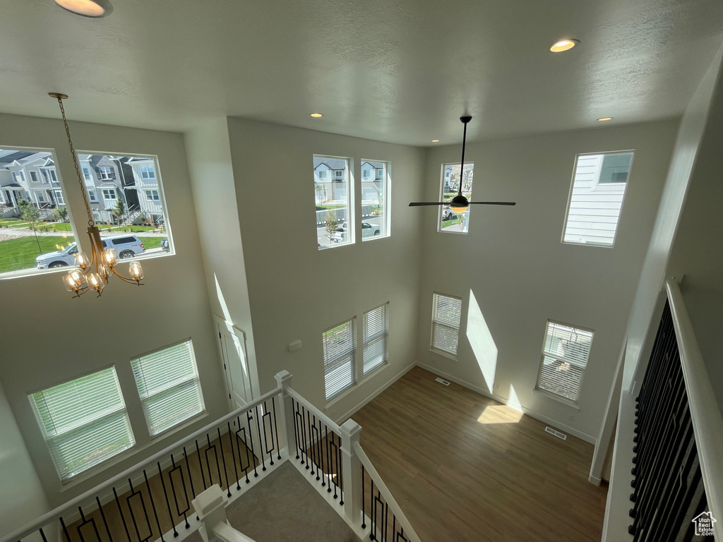 Stairs featuring recessed lighting, a ceiling fan, wood finished floors, a towering ceiling, and a chandelier